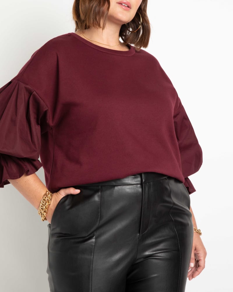 Front of a model wearing a size 14/16 Juniper Flounce Sleeve Sweatshirt in Syrah by ELOQUII. | dia_product_style_image_id:236503